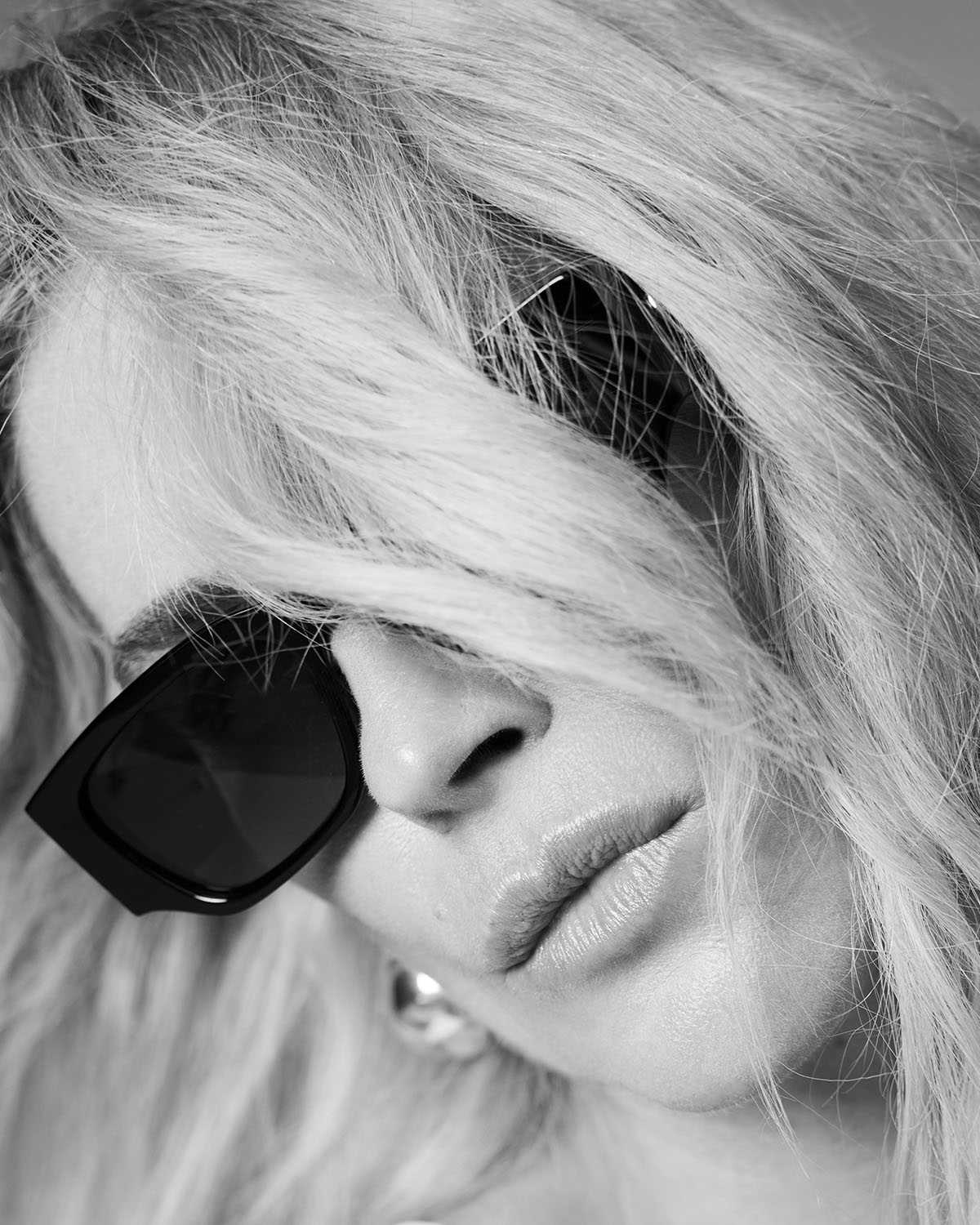 Lunettes de soleil monture noire logo AB sur les branches lndio Anine Bing. Porté par Erin Wasson. Photo noir et blanc.