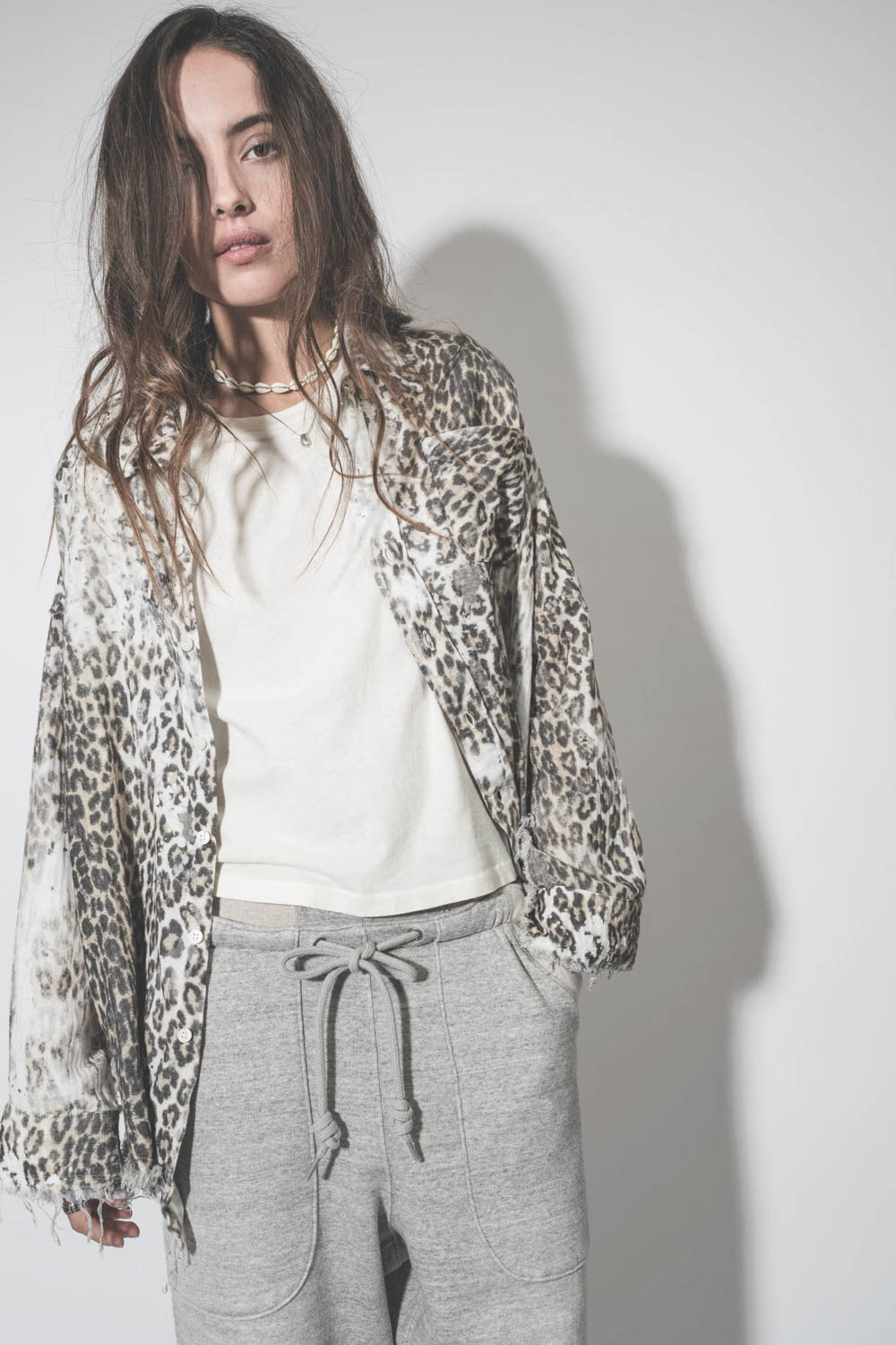 Chemise oversize en coton imprimé léopard délavé bord franc Shredded léopard R13. Porté ouverte sur un tee-shirt écru.