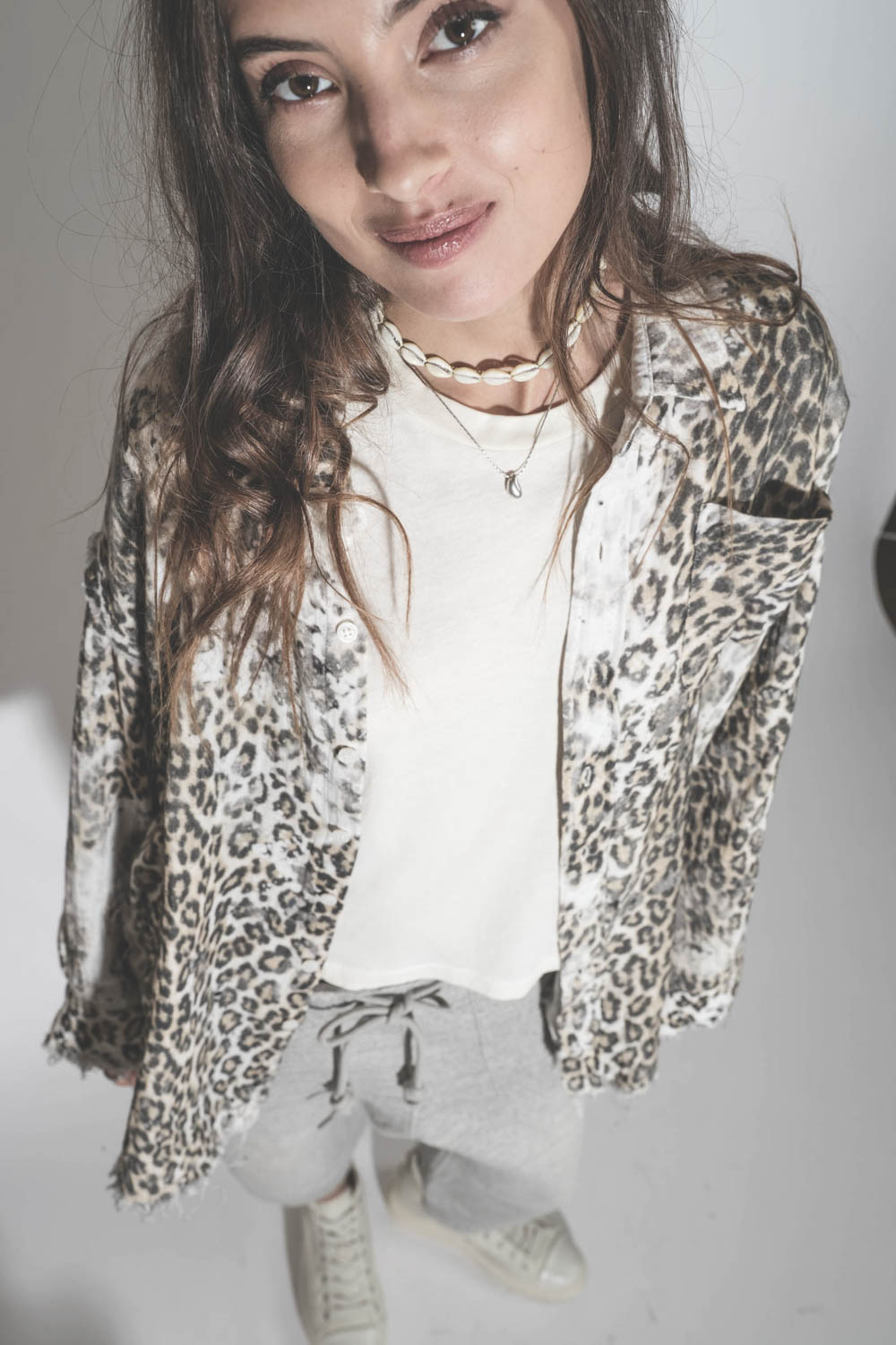 Chemise oversize en coton imprimé léopard délavé bord franc Shredded léopard R13. Porté avec un collier coquillage. 