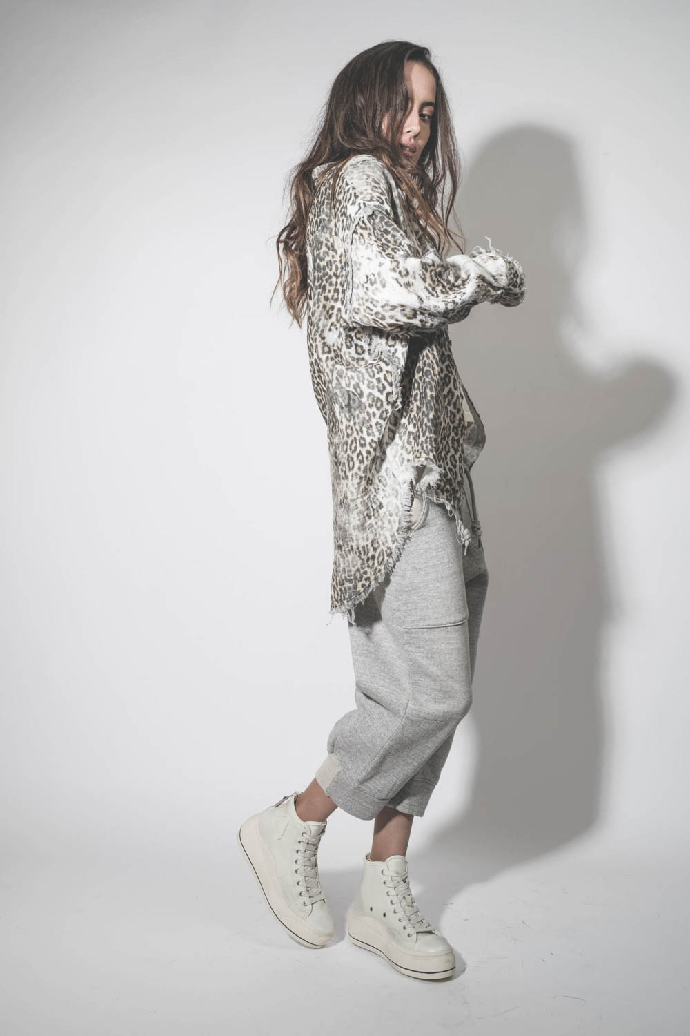 Pantalon de jogging court et oversize en molleton gris chiné Deconstructed Cropped Sweatpant Heather Grey R13. Porté de profil avec une chemise léopard.