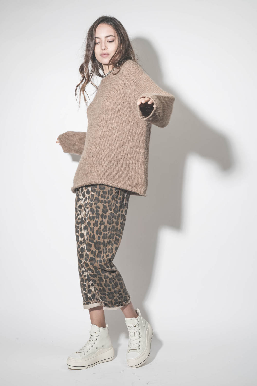 Jean baggy Tailored Drop en jean léopard R13. Porté avec un pull en alpaga beige.