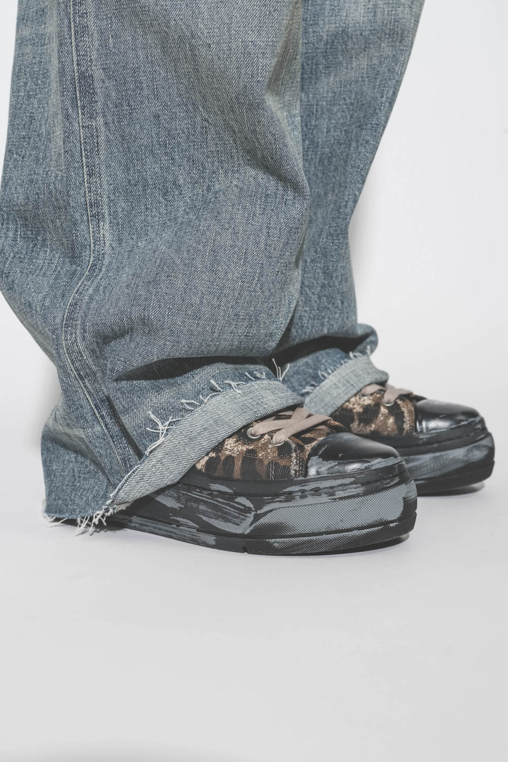 Sneakers compensées en toile léopard Kurt R13. Porté avec une salopette en jean bleu.